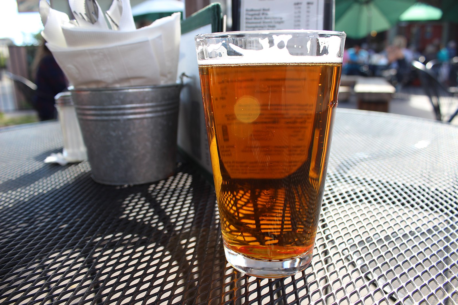 a glass of beer on the round black table outside