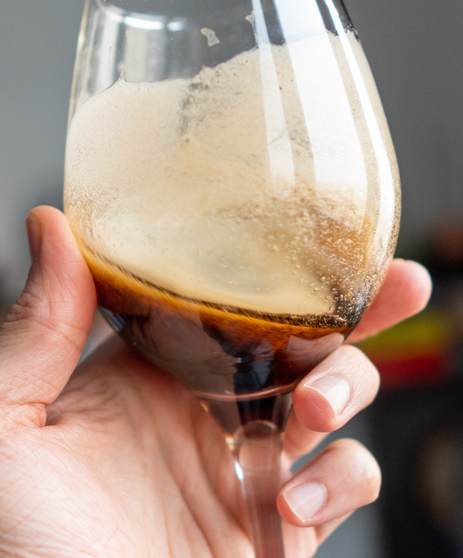 man's hand holding a glass of oatmeal stout 