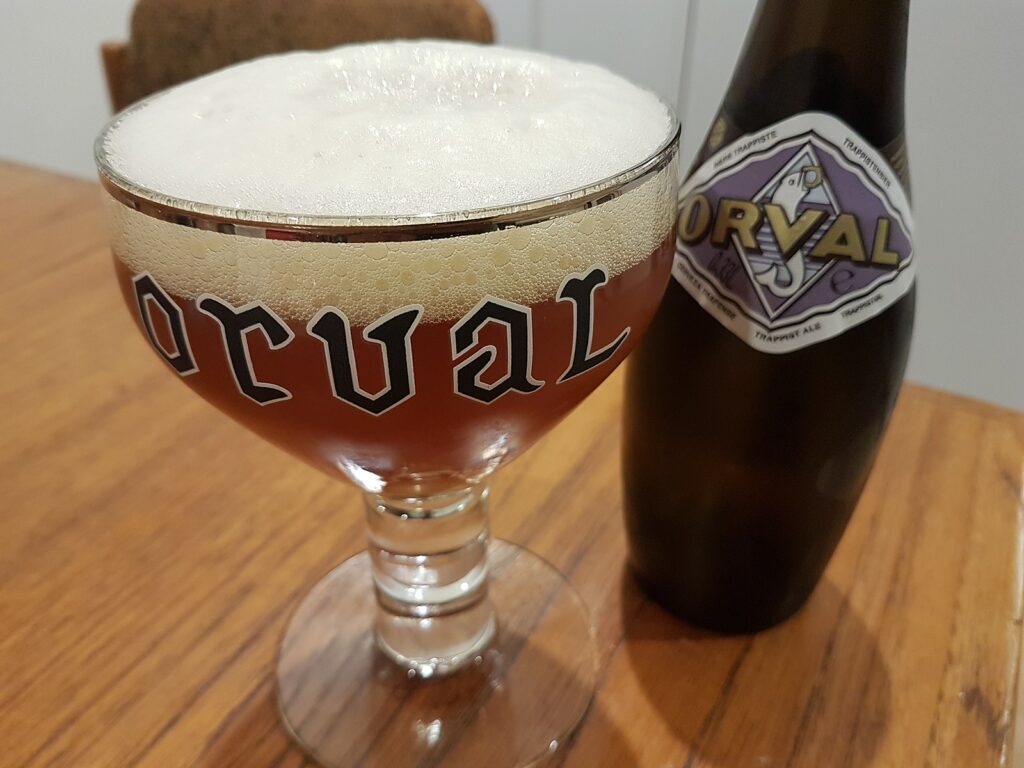 An Orval Trappist Ale bottle with a traditional glass