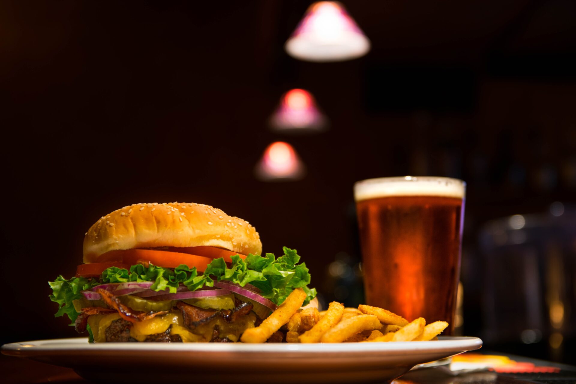 burger and fries on the plate against the glass of beer 