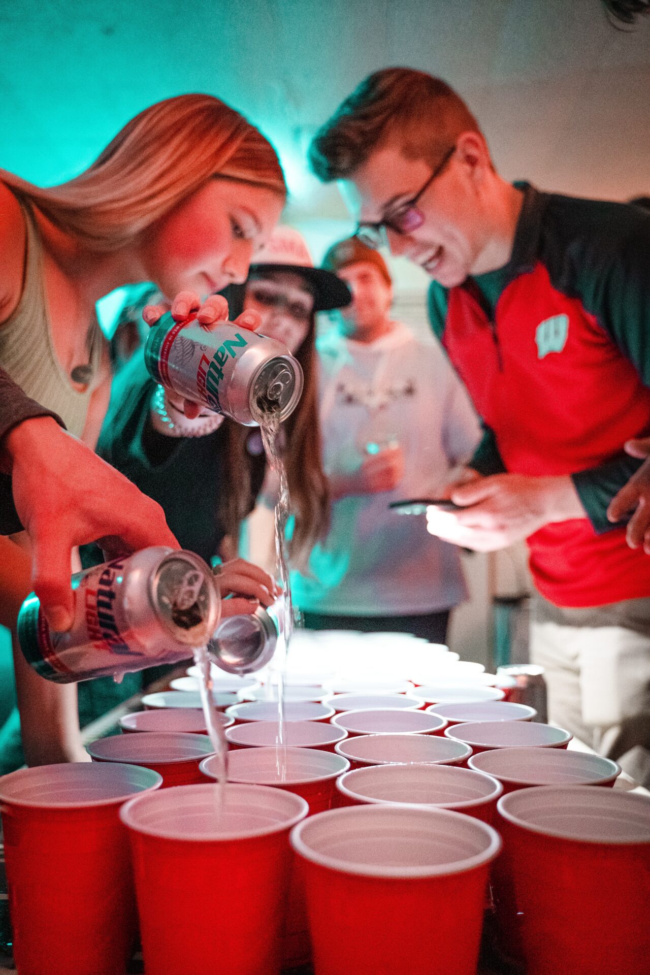 guys and girls pouring beer into plastic cups